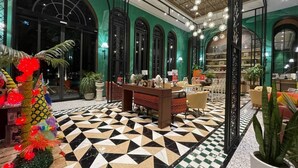 A lobby with a geometric patterned floor, a reception desk, and green walls.