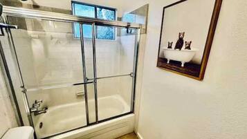 A bathroom with a glass-enclosed shower, a toilet, and a sink.