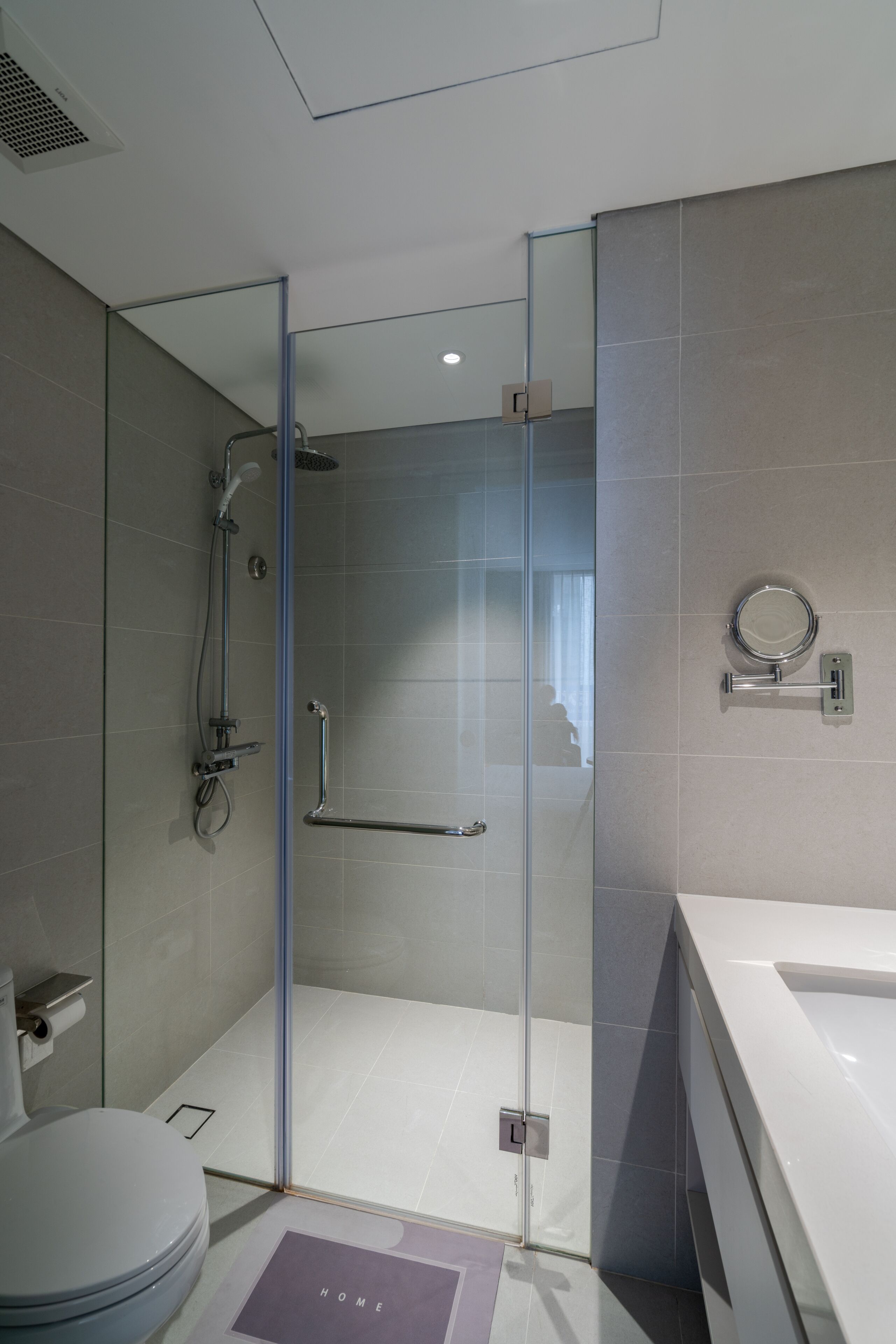 A modern bathroom with a glass-enclosed shower, a white toilet, and a large mirror.