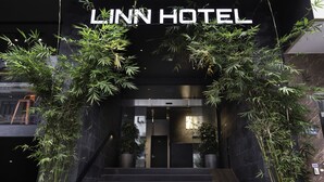 La entrada del Hotel Linn con un diseño moderno, que incluye una escalera y plantas grandes en macetas.