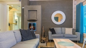 Una sala de estar moderna con un sofá gris, una mesa de centro de madera y una chimenea.