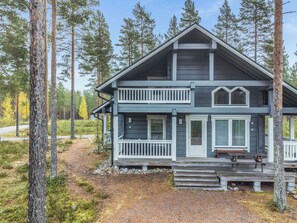 Une cabane à deux étages avec un balcon, entourée d’arbres.