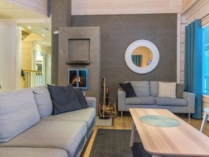 Ein modernes Wohnzimmer mit zwei grauen Sofas, einem Holztisch, einem Kamin und einem runden Spiegel an der Wand.