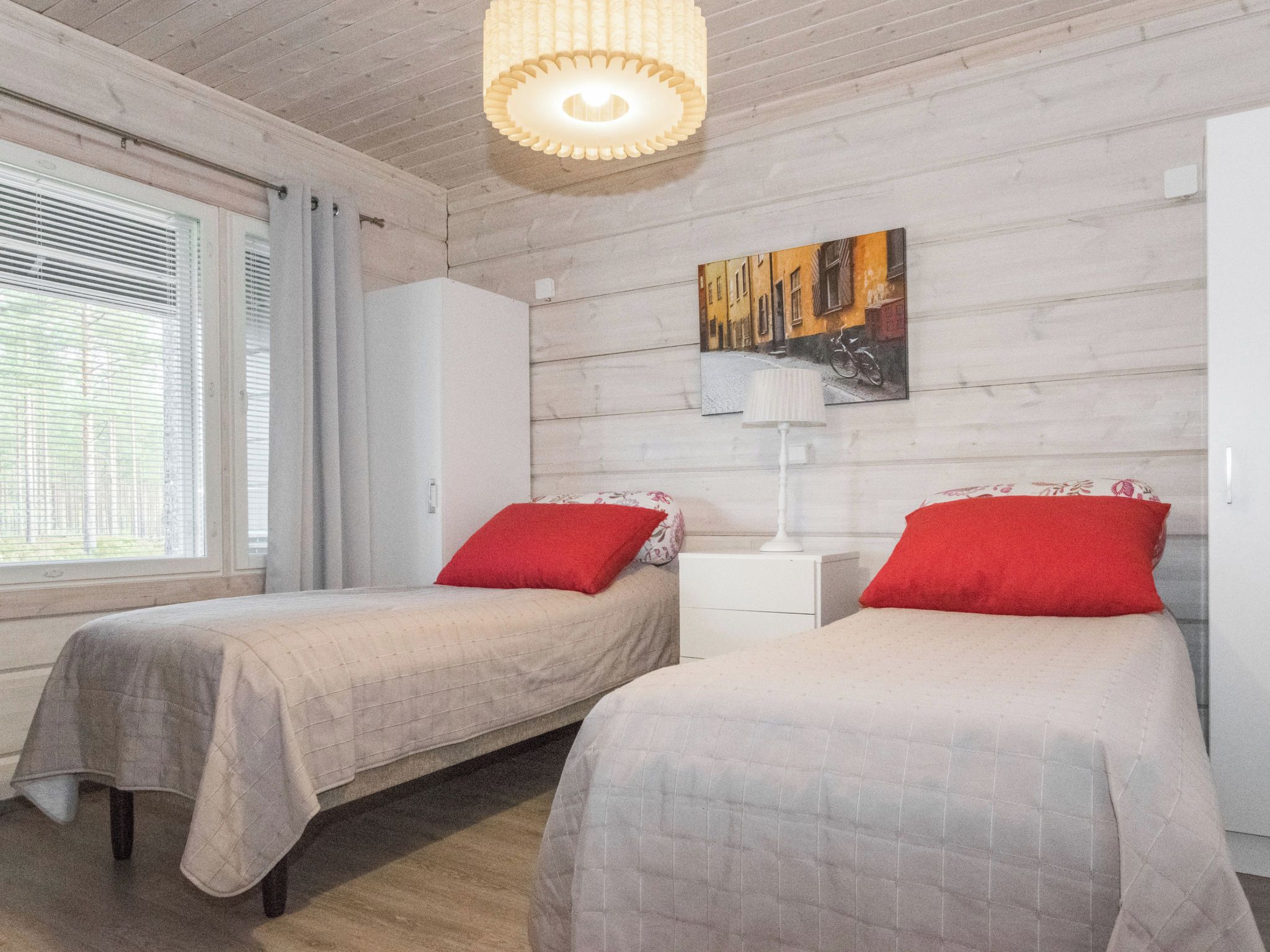 Un dormitorio con dos camas, una mesita de noche, una lámpara y un cuadro en la pared.