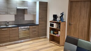 A modern kitchen with wooden cabinets, a stainless steel sink, and a microwave. - Meublés du 25 N°5 à Niederbronn-les-bains (Niederbronn-les-Bains)