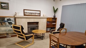 A living room with a fireplace, a round wooden table, and two chairs. - Kybunga by the Beach (part of Harriett's Cottage) (Largs North)