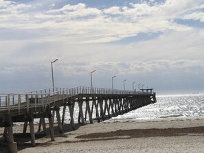 Um cais que se estende para o mar, com uma passarela e postes de luz.