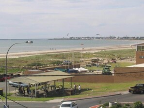 A coastal area with a beach, a parking lot, and a covered seating area.