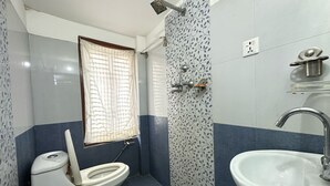 Un baño con inodoro, lavabo, ducha y ventana.