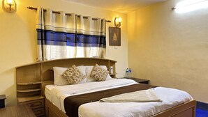 Una cama bien tendida con almohadillas florales, un cabecero de madera y una mesita de noche con una botella de agua.