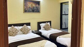 Habitación de hotel con dos camas, un cuadro en la pared y una puerta con un espejo que refleja la habitación.