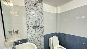 Un baño con lavamanos blanco, inodoro y ducha.