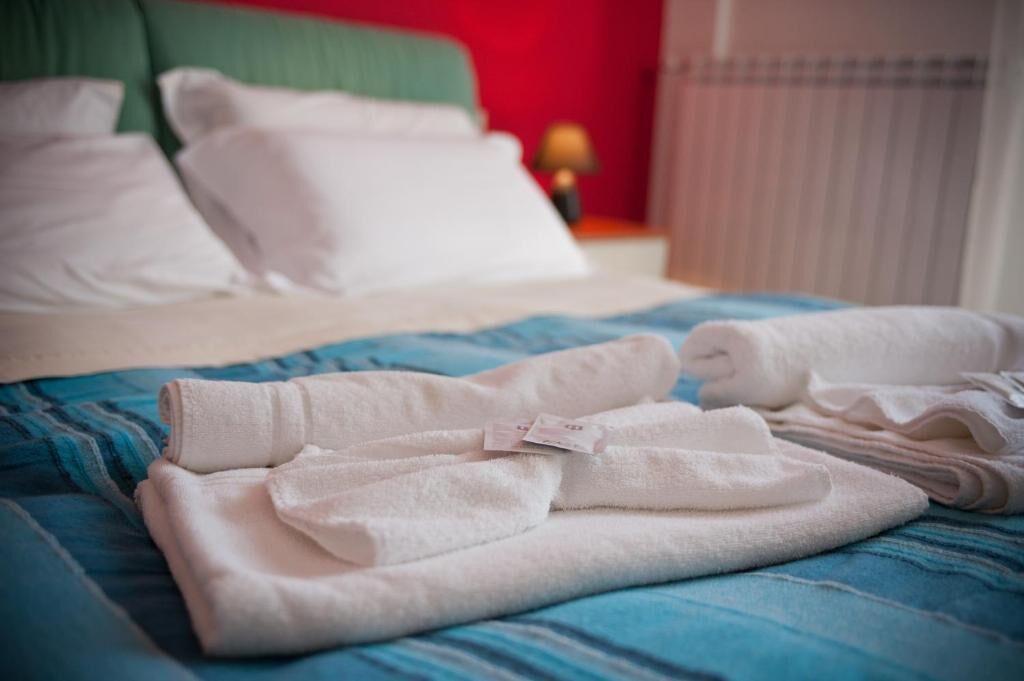 A neatly made bed with white pillows and folded towels on a blue striped bedspread.