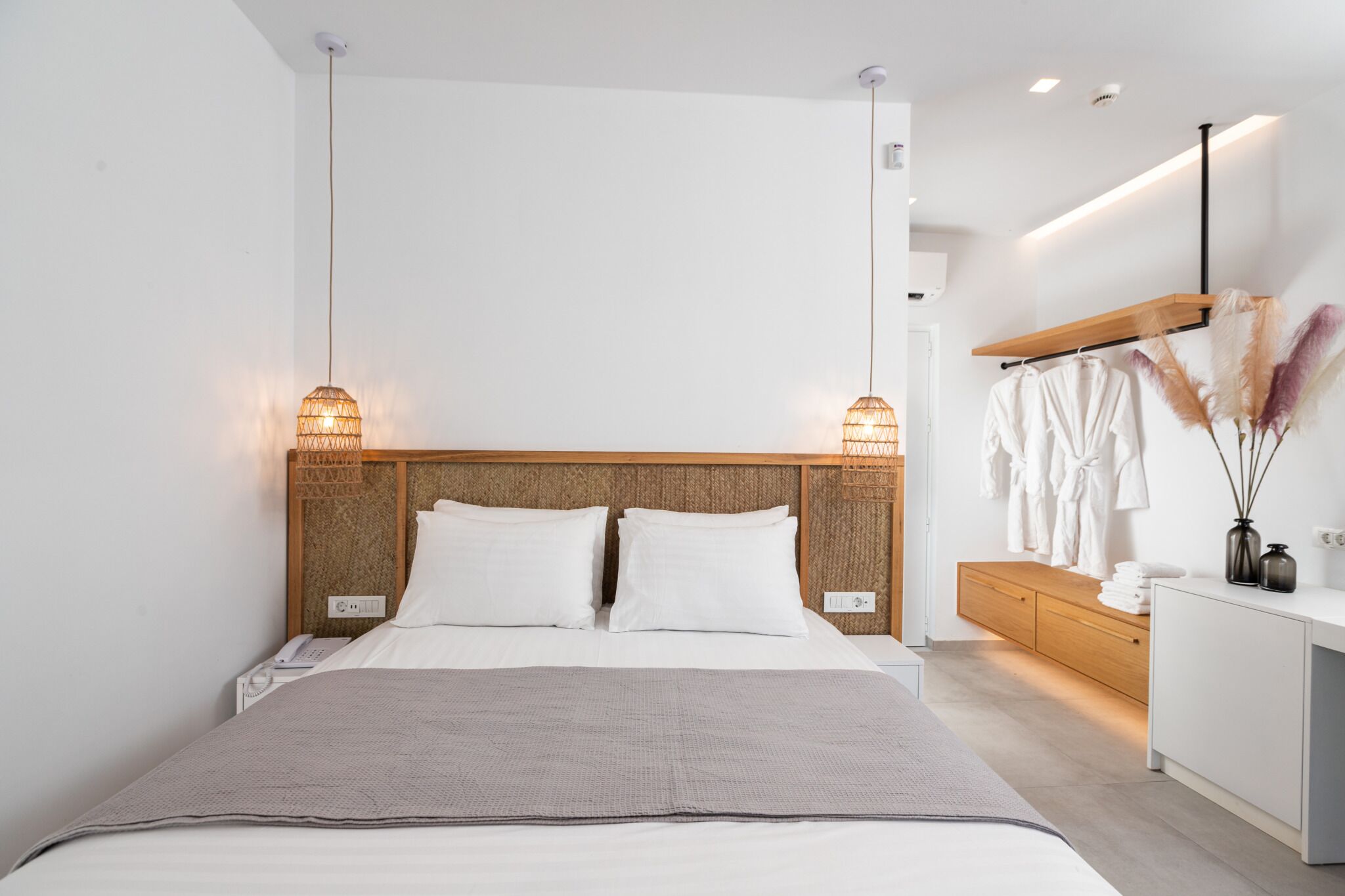 Une chambre à coucher moderne avec un grand lit, des lampes de chevet, une tête de lit en bois, une table de chevet et une armoire.