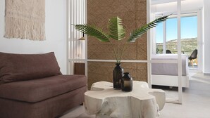 A modern living room with a brown sofa, a white coffee table with a plant, and a large window with a view of the outdoors. - Myzith Luxury Suites (Zakynthos)