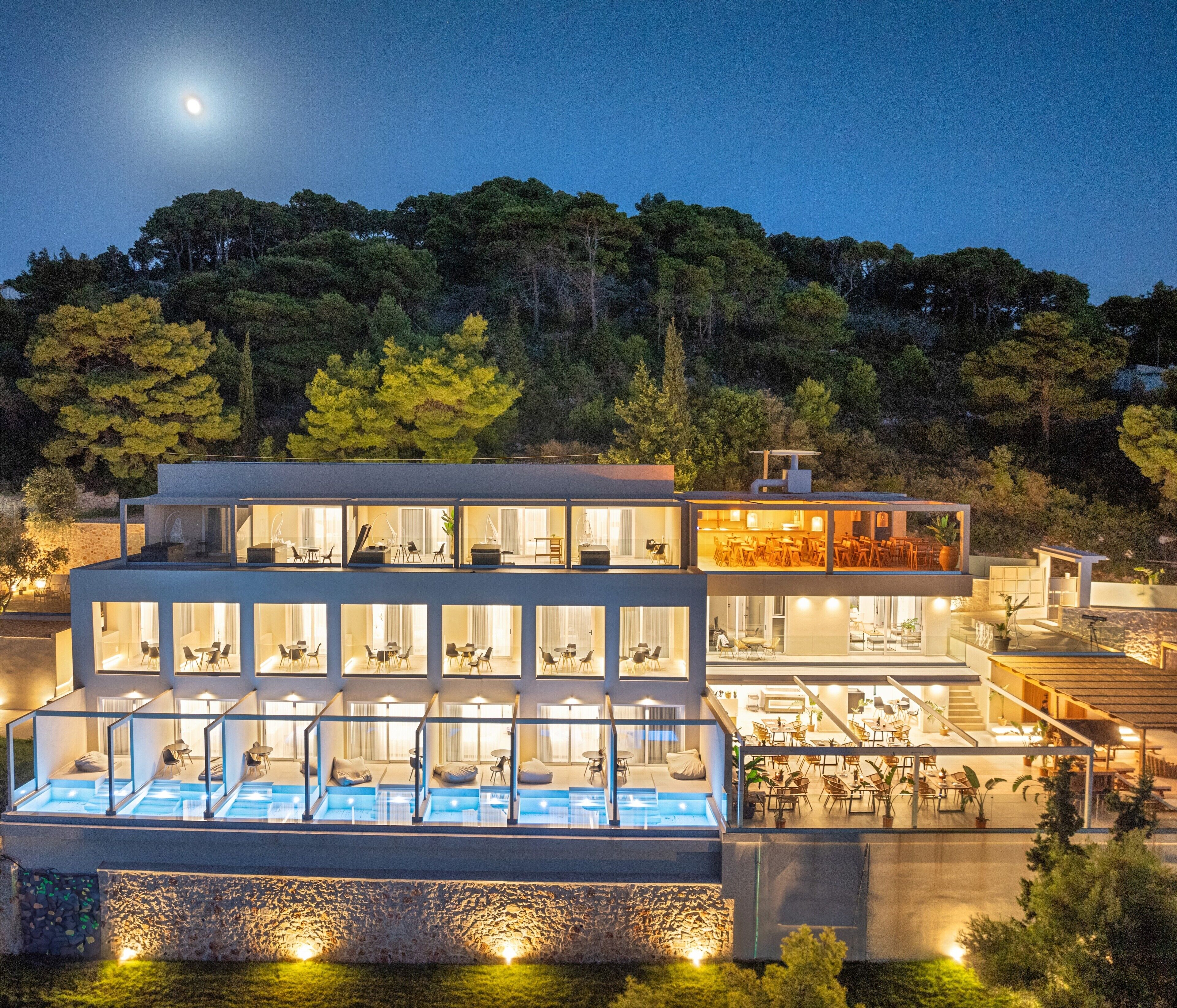 A modern hotel with multiple levels, outdoor seating, and a swimming pool.