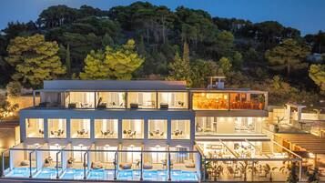 A modern hotel with multiple levels, outdoor seating, and a swimming pool.