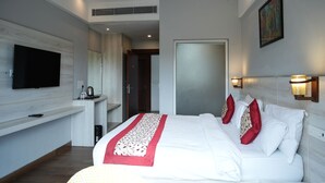 A modern hotel room with a large bed, a flat-screen TV, a small desk, and a painting on the wall. - AAR Resort and Spa (Dehradun)