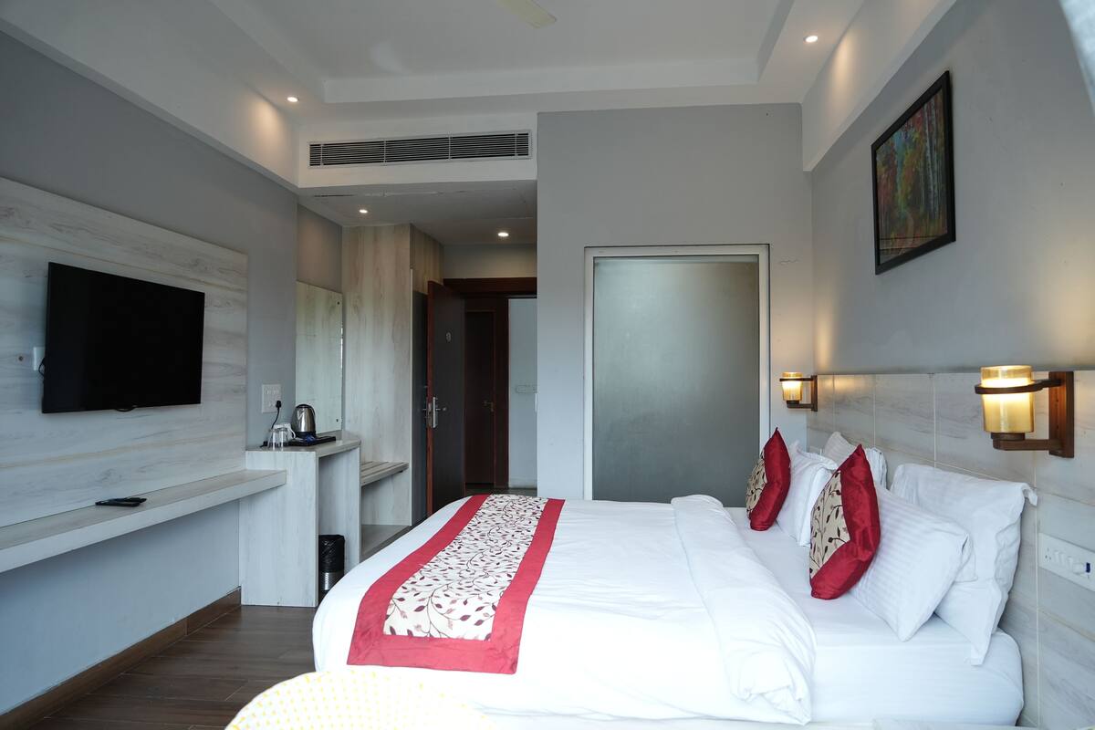 Een moderne hotelkamer met een groot bed, een flatscreen televisie, een klein bureau en een schilderij aan de muur.