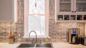 A kitchen with a double sink, a coffee maker, and a cabinet with glass doors. - Delightful 2bdrm Church w/Incredible Water View!

 (Prince Edward)