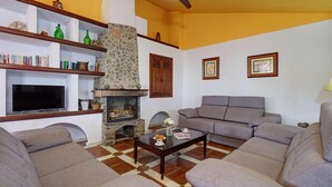 Una sala de estar con chimenea, televisor, sofá y mesa de centro.