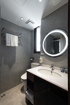 A modern bathroom with a white sink, a round mirror, and a towel rack. - Hotel Euphemia (Taichung)