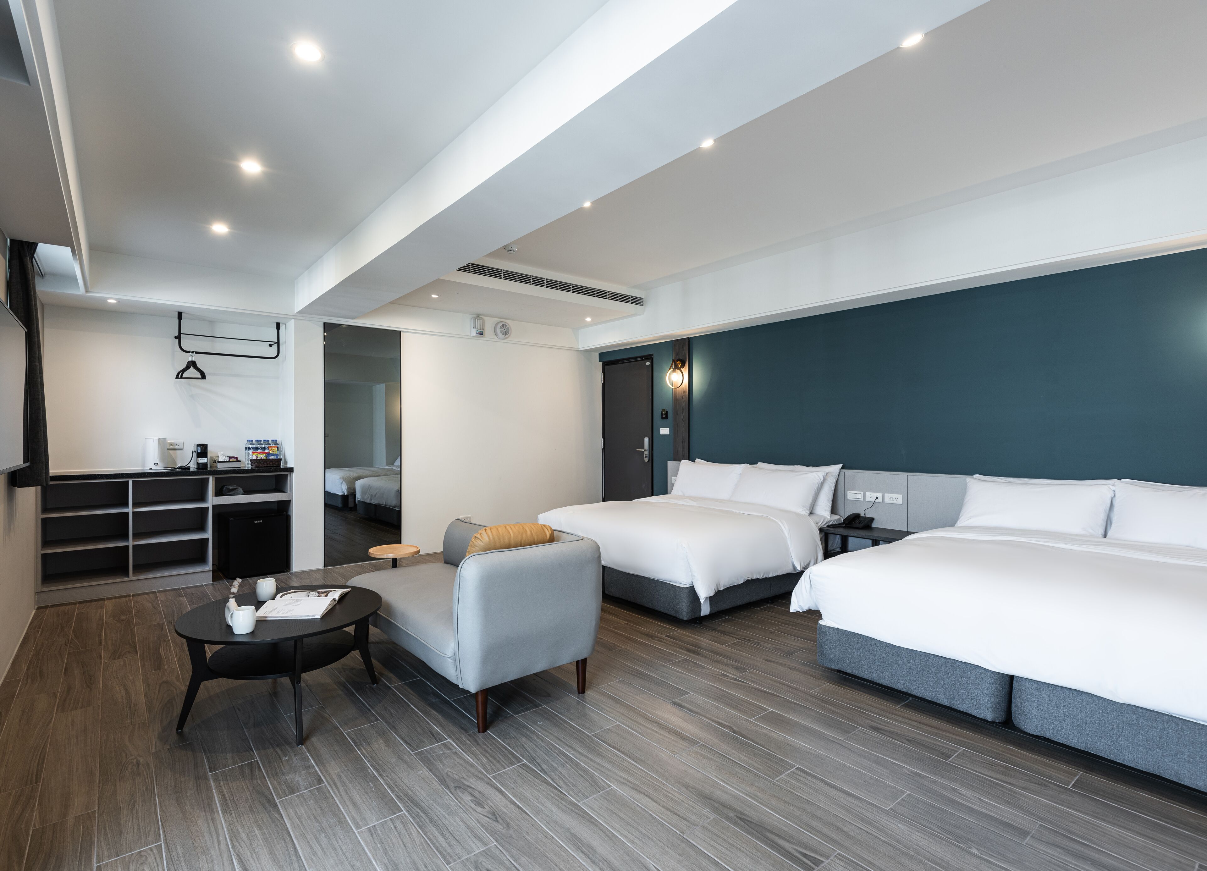 Une chambre d’hôtel moderne équipée de deux lits, d’un canapé, d’une petite table et d’un bureau avec un ordinateur.