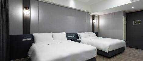 Habitación de hotel con dos camas, un cabecero oscuro, una lámpara fijada a la pared y un panel de control en la pared.