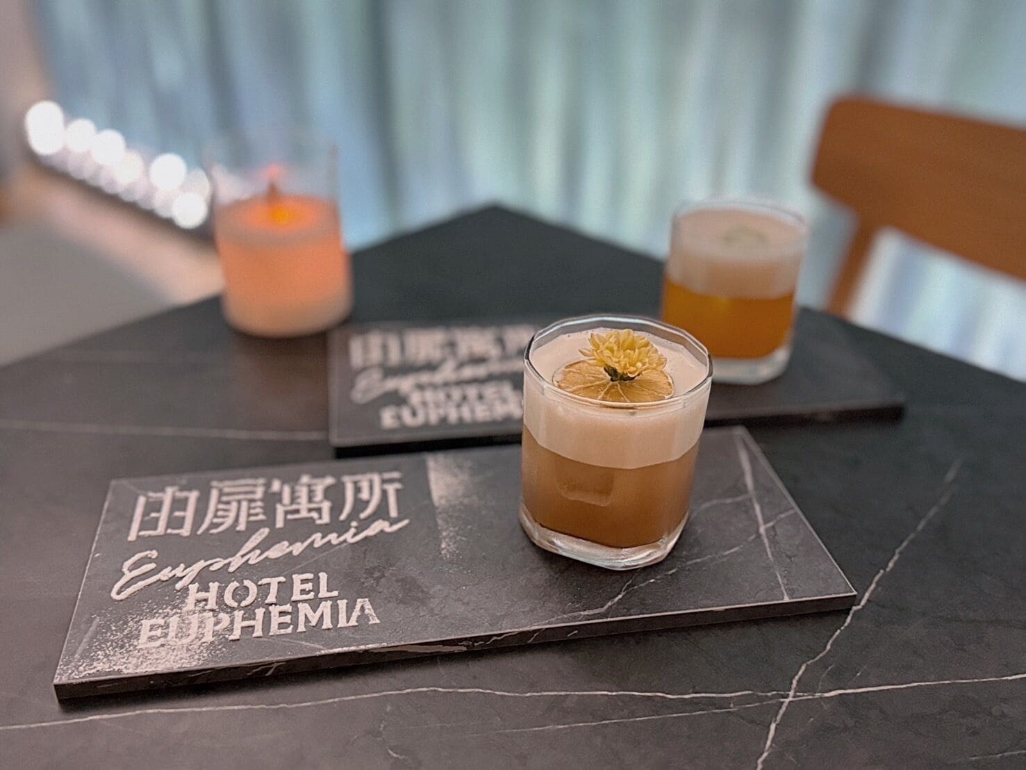 Two glasses of cocktails on a table with a menu.