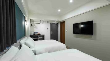 Une chambre d’hôtel avec deux lits, une télévision, un bureau avec une chaise et une porte.