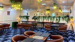 A conference room with tables and chairs, hanging plants, and ceiling lights.