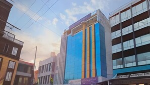 A modern building with a glass facade, a sign for 'Hotel Paradise', and a parked motorcycle.