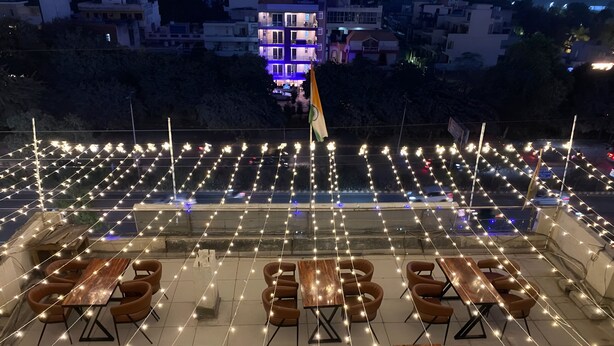 An outdoor dining area with multiple tables and chairs, string lights, and a flag.
