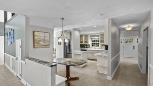 A modern kitchen with white cabinetry, a marble countertop, and stainless steel appliances. - Stay Awhile by AvantStay | Lakefront + Pool, Dock (Mooresville)