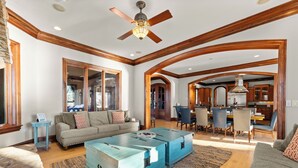A spacious living room with a large coffee table, a sofa, and a dining area with chairs and a table.