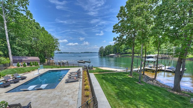 A swimming pool with lounge chairs, a dock, and a lake view. - Private Dock, Boat Ramp, Saltwater Pool & Waterfront Firepit | Bright Water Cove (Denver)