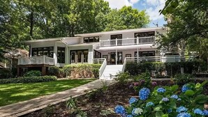 A two-story house with a front porch, a covered walkway, and a landscaped garden with hydrangeas. - Lakefront Home w/ Prv. Dock, Tiki Bar & Firepit | Shore to Please by AvantStay (Denver)