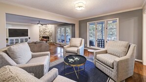 A spacious living room with a fireplace, comfortable seating, and large windows. - Lakefront Home w/ Prv. Dock, Tiki Bar & Firepit | Shore to Please by AvantStay (Denver)