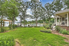 A well-maintained backyard with a lawn, a wooden pergola, and a view of a lake. - Lakefront Retreat • Hot Tub + Game Room + Dock | A Frame of Mind (Sherrills Ford)