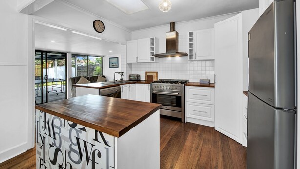 A modern kitchen with white cabinetry, a built-in stove, and a large refrigerator.