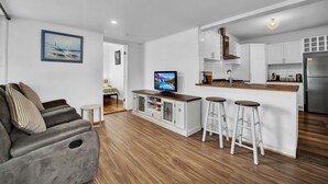 A modern kitchen with white cabinets, a stainless steel refrigerator, and a wooden island with bar stools.