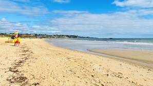 A sandy beach with a clear sky and a distant view of a town.