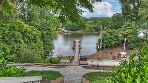 A view of a lake with a dock, surrounded by lush greenery and a stone staircase leading to a dock. - Lakefront w/ Private Dock + Hot Tub | Pontoon Rental | Butler Bliss by AvantStay (Sherrills Ford)
