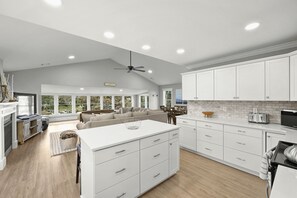 A spacious kitchen with white cabinetry, a large island, and a dining area with a sofa and table.