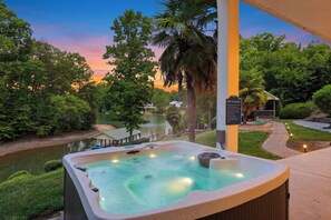 A hot tub with a view of a lake and trees at dusk.
