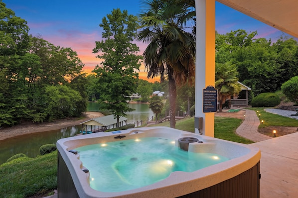 Un jacuzzi con vistas a un lago y árboles al anochecer.