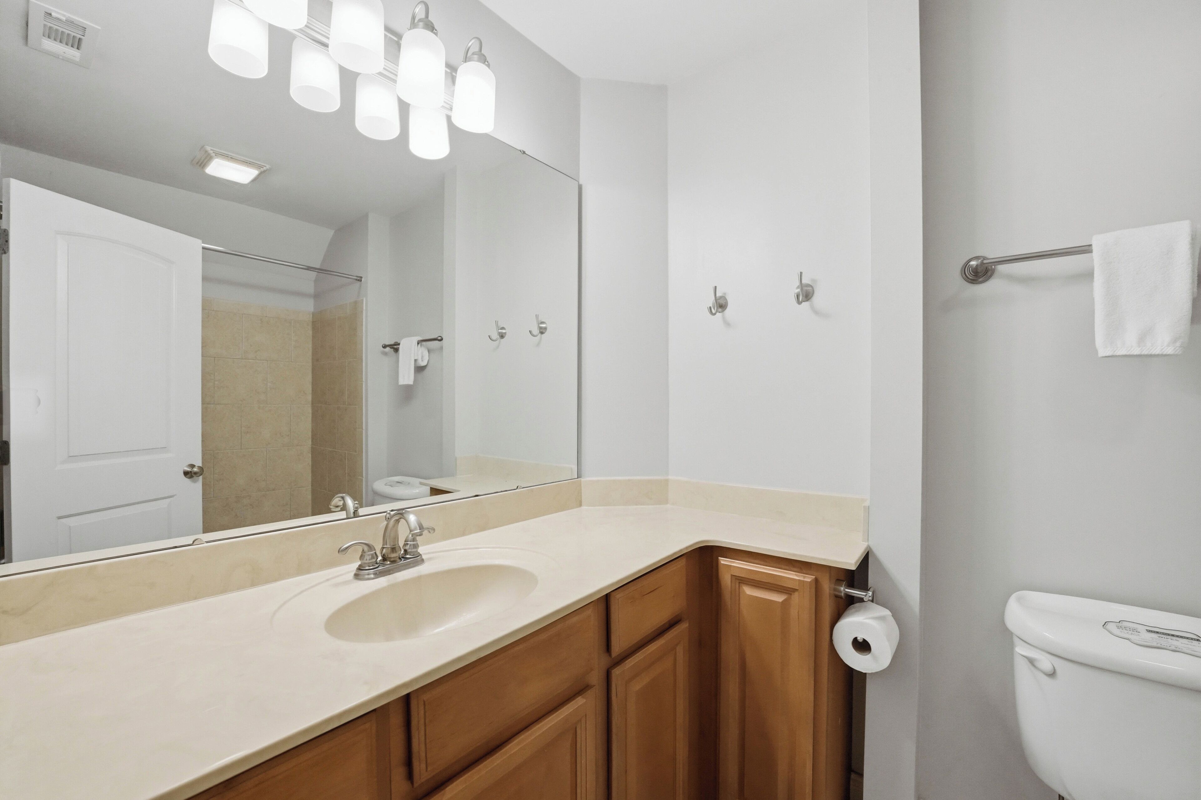 A bathroom with a sink, mirror, towel rack, toilet, and a shower door.