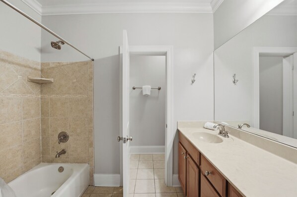 A bathroom with a bathtub, shower, vanity with a sink, and a mirror.