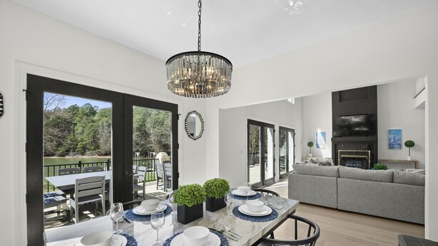 A dining area with a large table set for six, a chandelier, and a view of the outdoors. - Knotty Pines by AvantStay | Lake Views, Renovated (Sherrills Ford)
