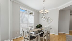 A dining area with a table, chairs, a chandelier, and a window with blinds. - Kool Breeze by AvantStay | Boat Ramp + Hot Tub (Denver)